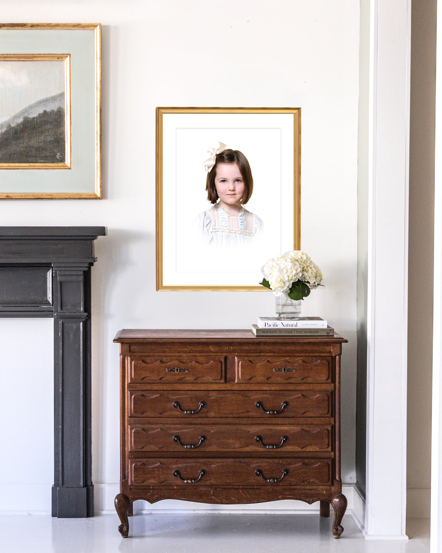 Wooden dresser with a custom framed heirloom portrait and flowers against a white wall.