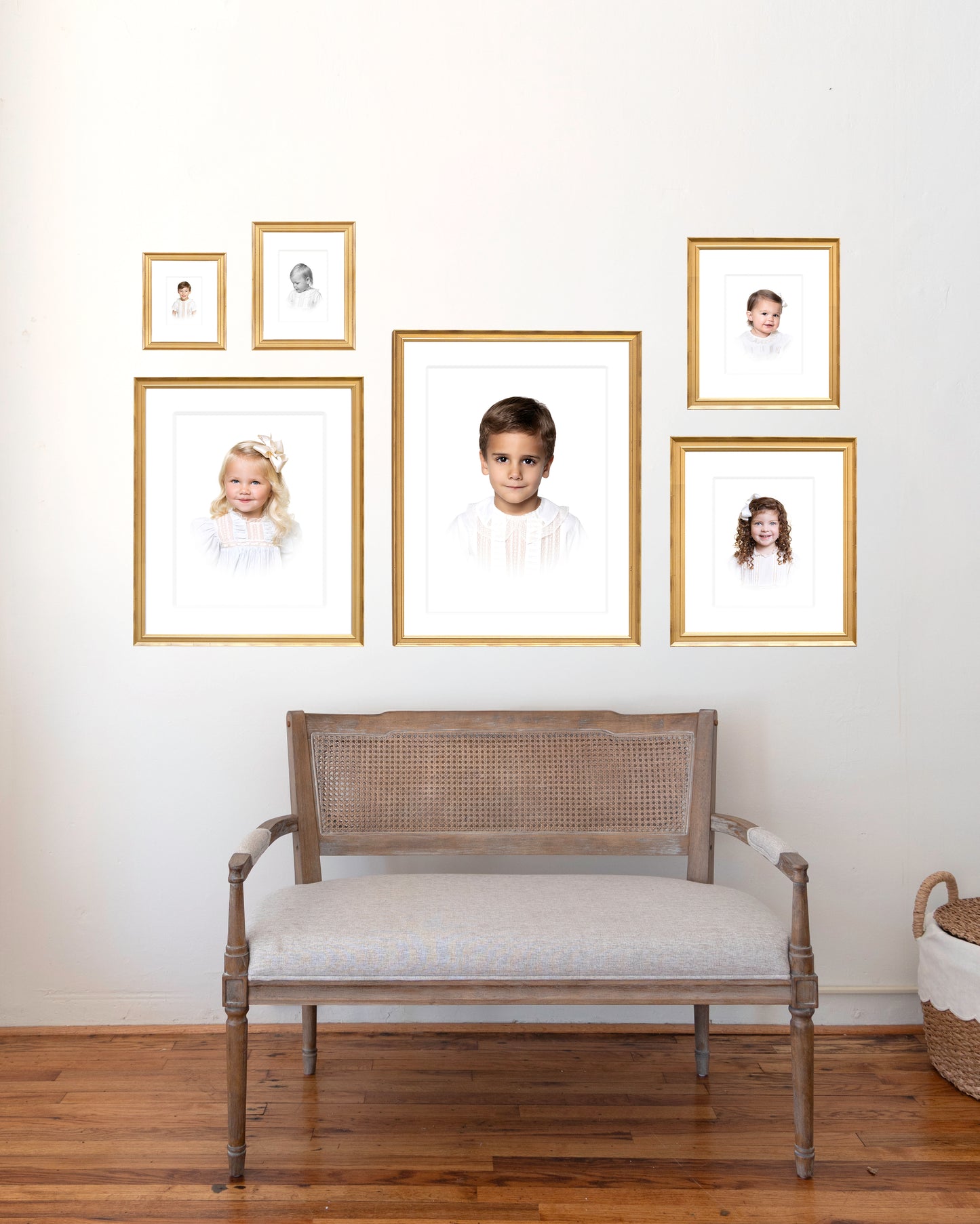 Wall with custom framed heirloom portraits of children and a bench below to show the scale
